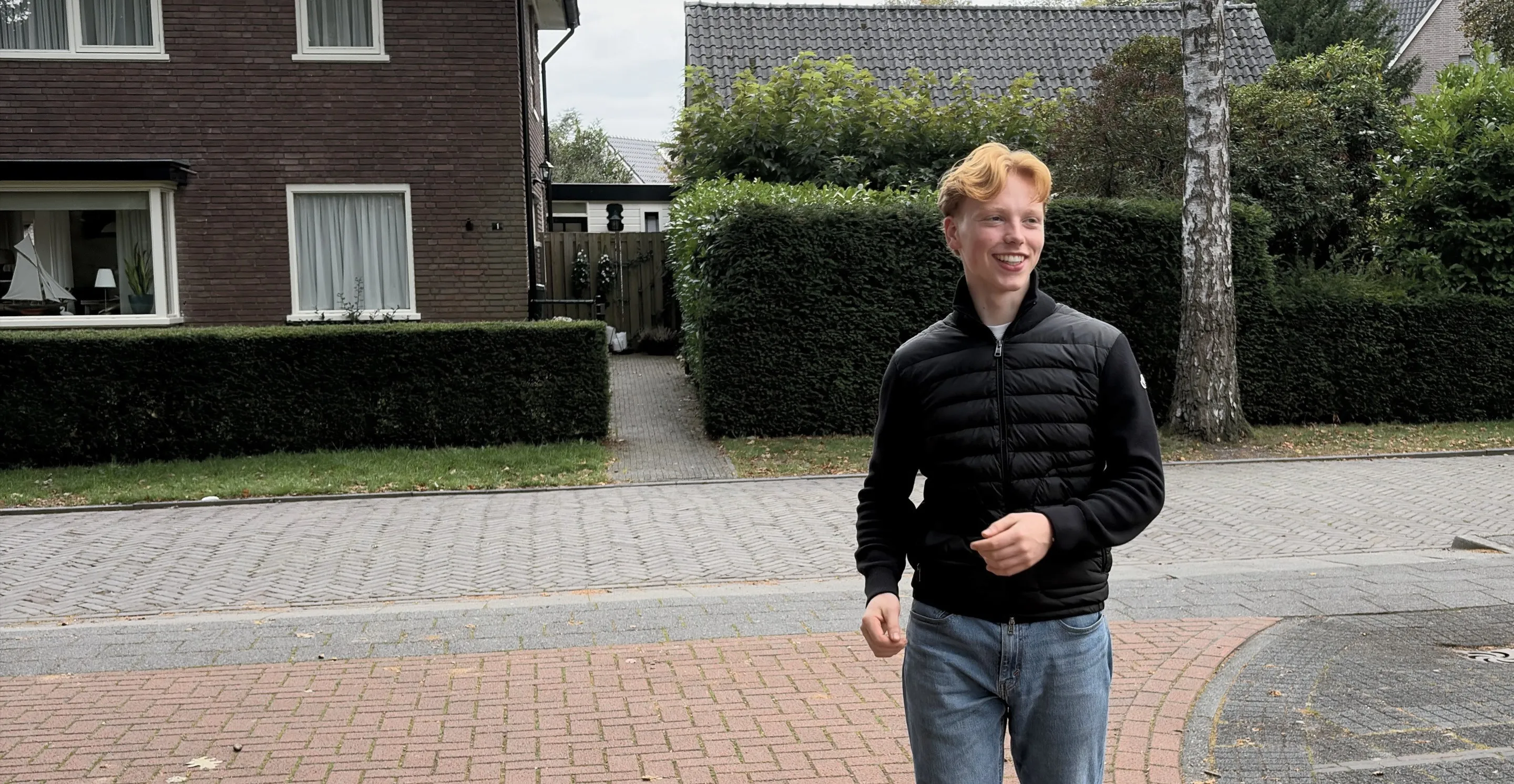 Maarten Kok buiten op straat, lachend, in een zwarte jas