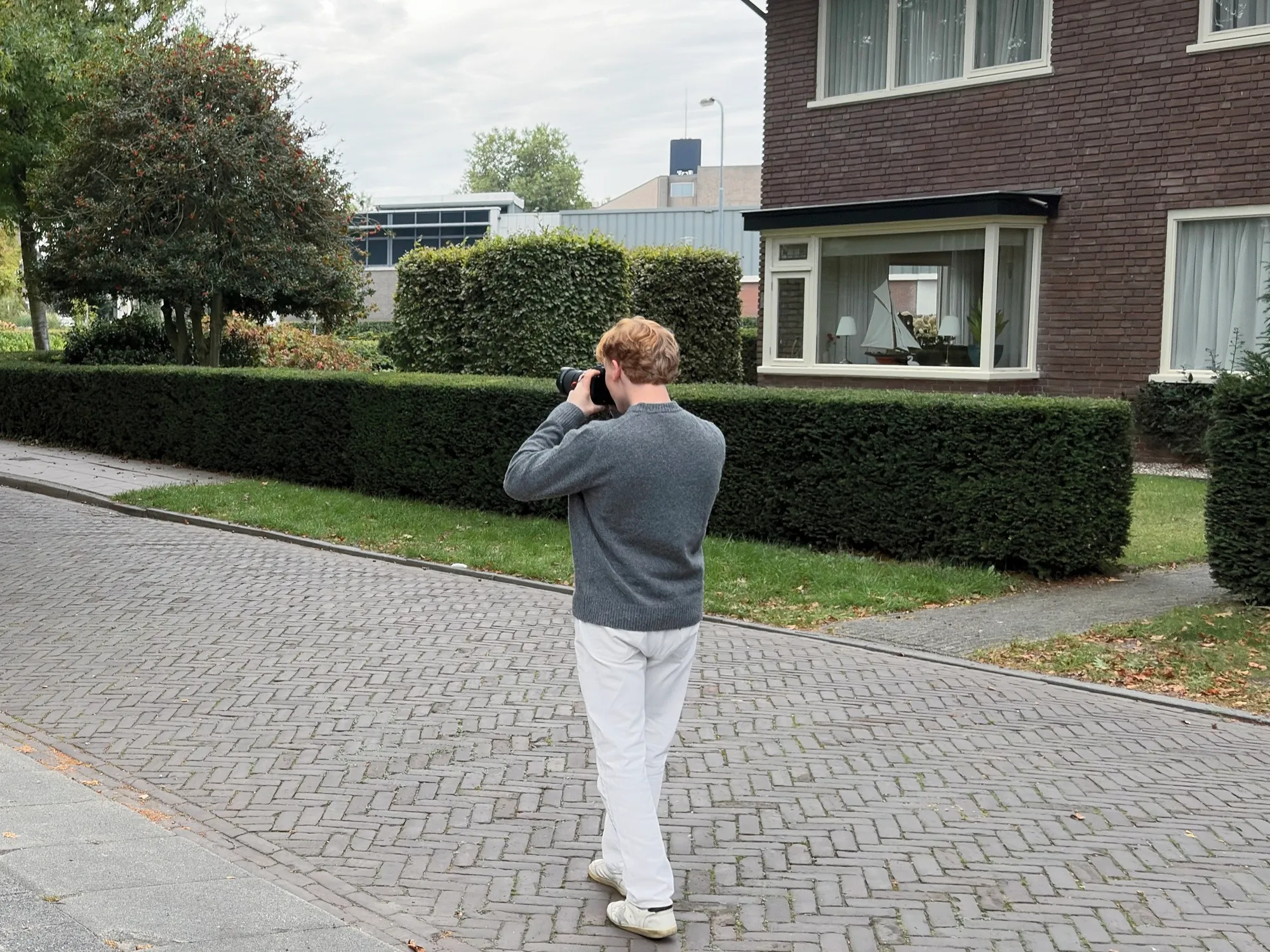 Maarten fotografeert vanaf de straat een woning met een camera